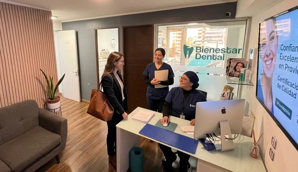 Recepción moderna de clínica dental en Providencia con personal profesional saludando a un paciente en un ambiente acogedor y limpio